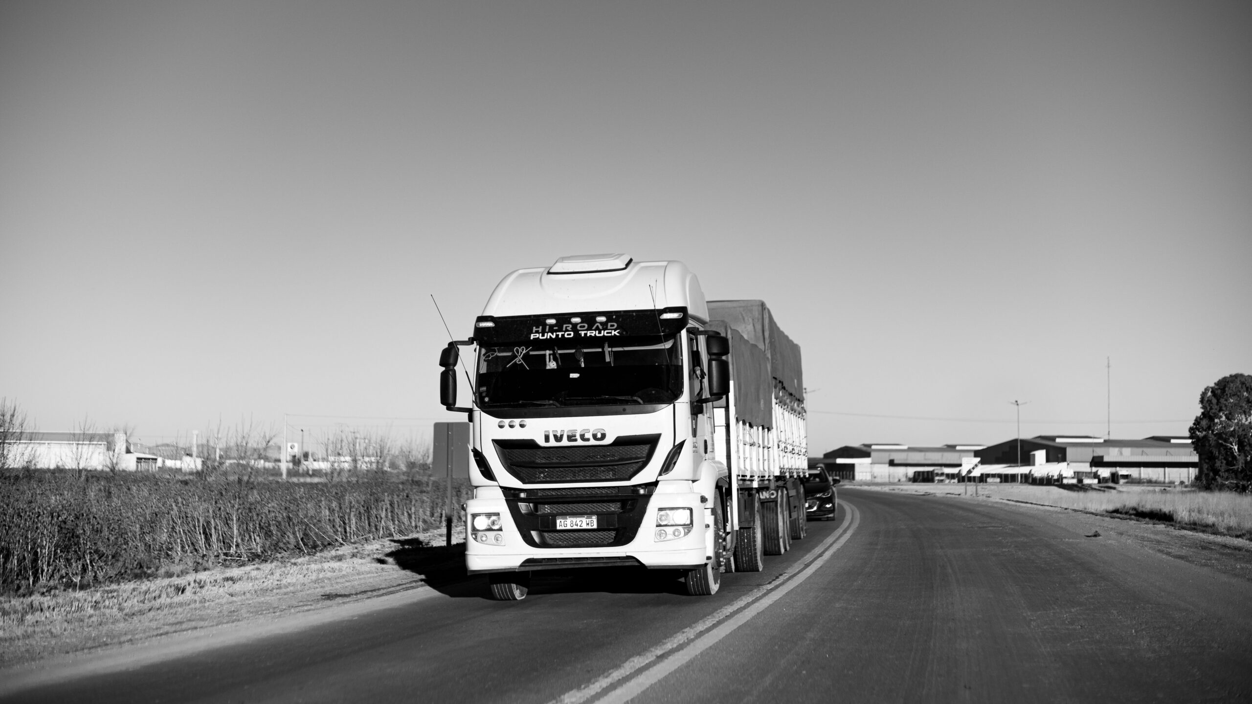 Black and white image of a freight truck on a one-lane highway