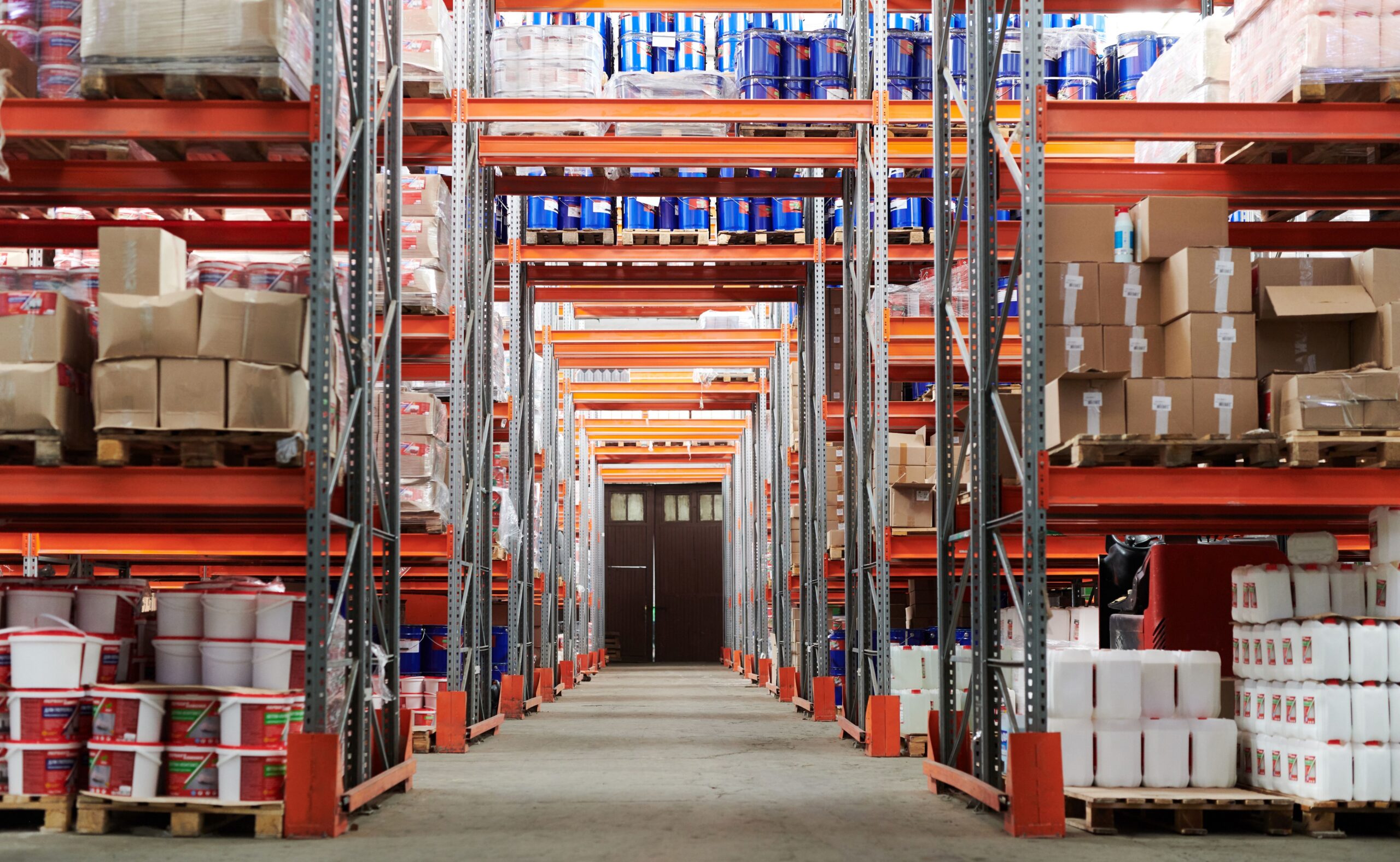 Warehouse interior with racks holding pallets of inventory in boxes and buckets.